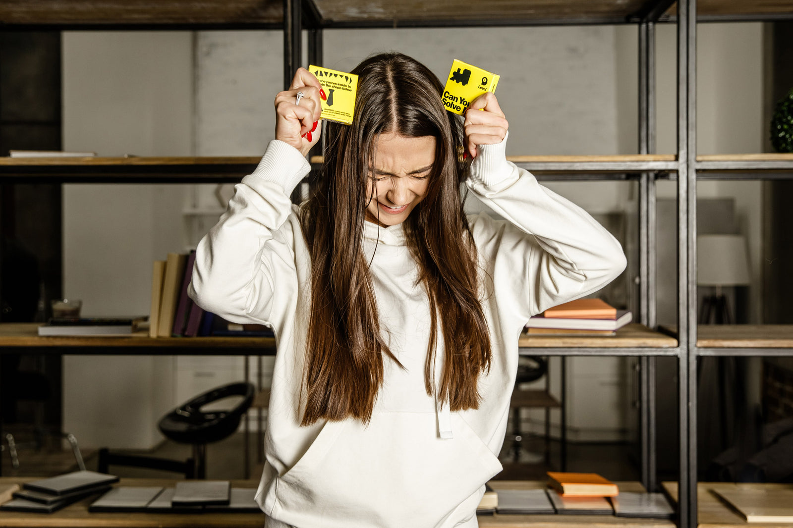 A puzzler holds two yellow Can You Solve Me? boxes during a playful solving challenge